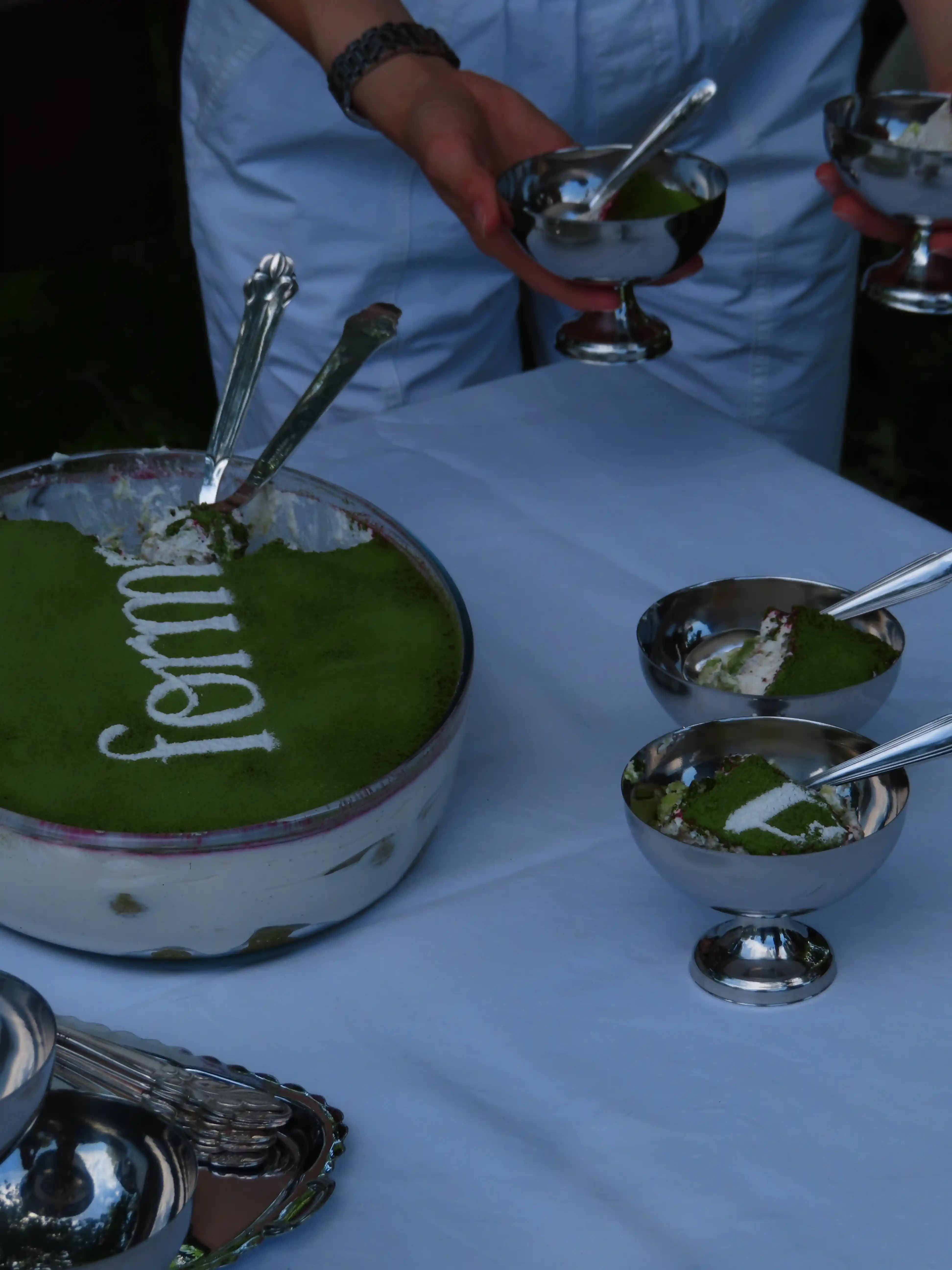 A Forma cake being served in silver dessert bowls at an outdoor gathering.